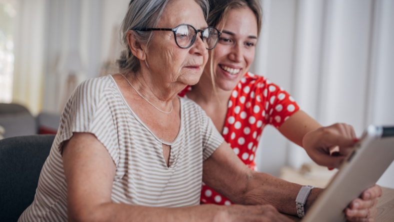 Elderly woman sitting with young girl at laptop