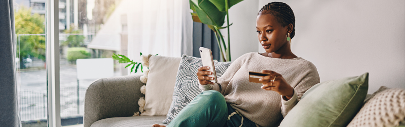 Woman relaxing on couch holding mobile phone and credit card