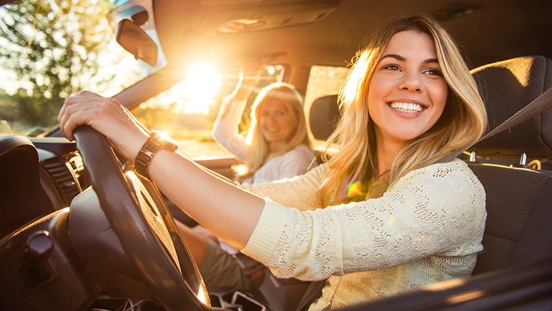 Young woman sitting in the drivers seat of a car.