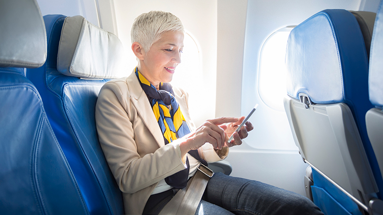 Woman looking at her phone sitting in an airplane seat