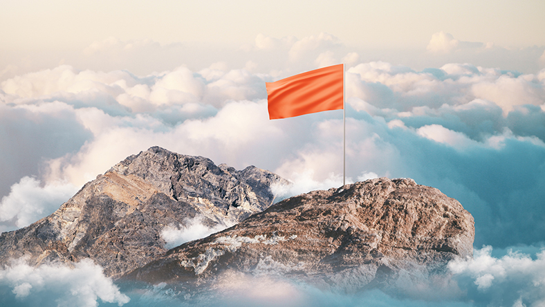 A flag on top of a mountain above the clouds