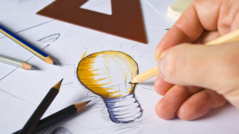 Person drawing a lightbulb on paper