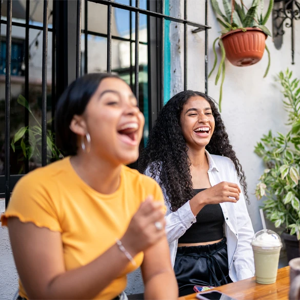 Two people sitting at an outdoor café table enjoying refreshments and conversation.