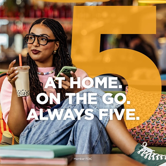 Person sitting in a lounge holding a drink and a phone with the text “At Home. On the Go. Always Five.”