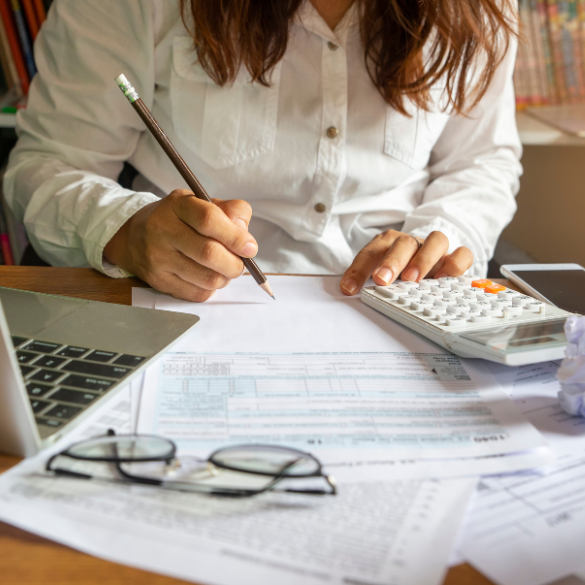 Woman at desk with calculator and documents.